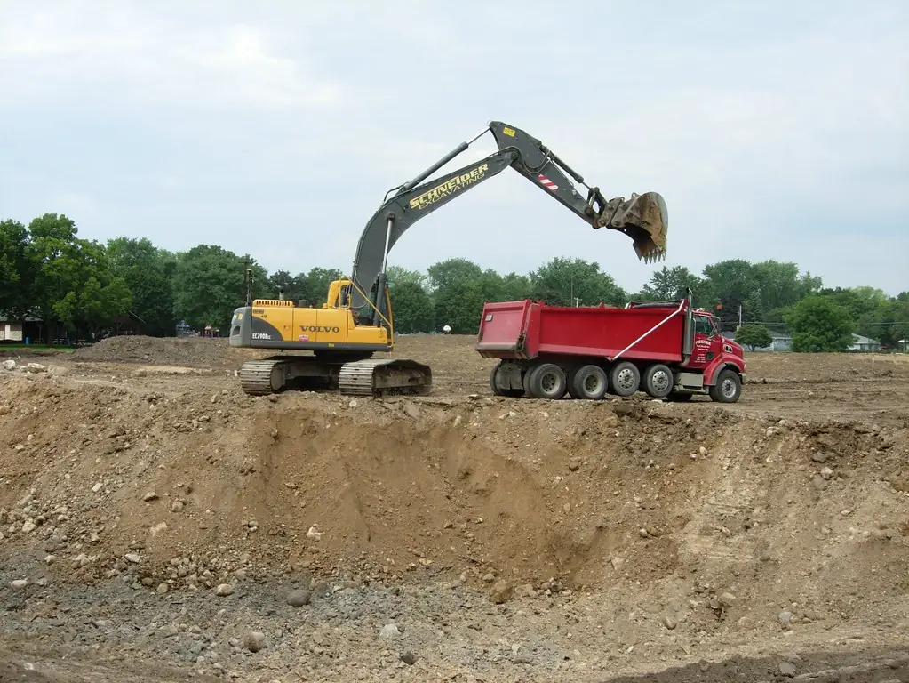 Excavator loading soil during sitework, used as representative stock photography